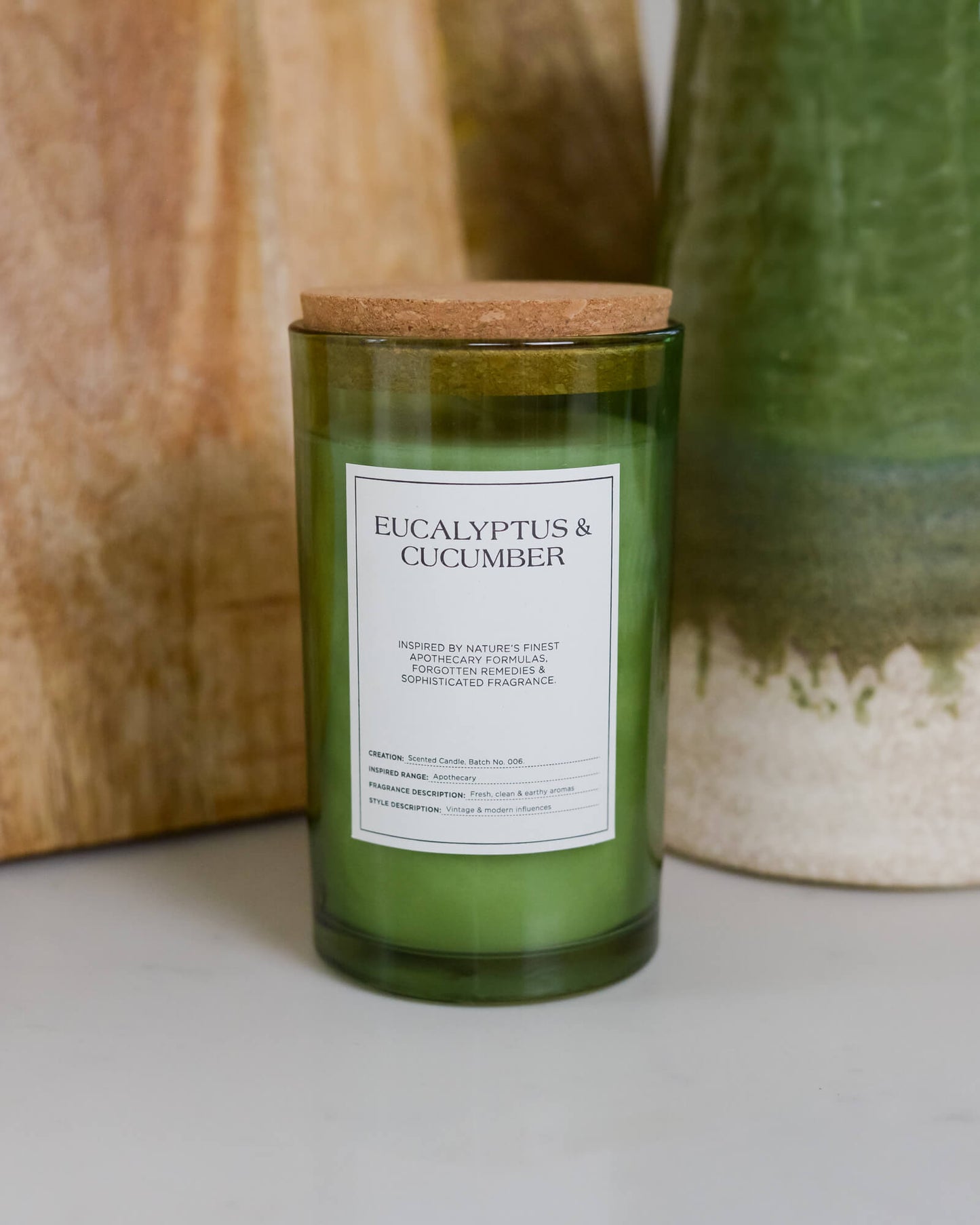Green candle labeled 'Eucalyptus & Cucumber' with a cork lid on a neutral background