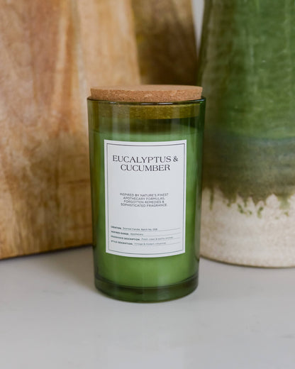 Green candle labeled 'Eucalyptus & Cucumber' with a cork lid on a neutral background