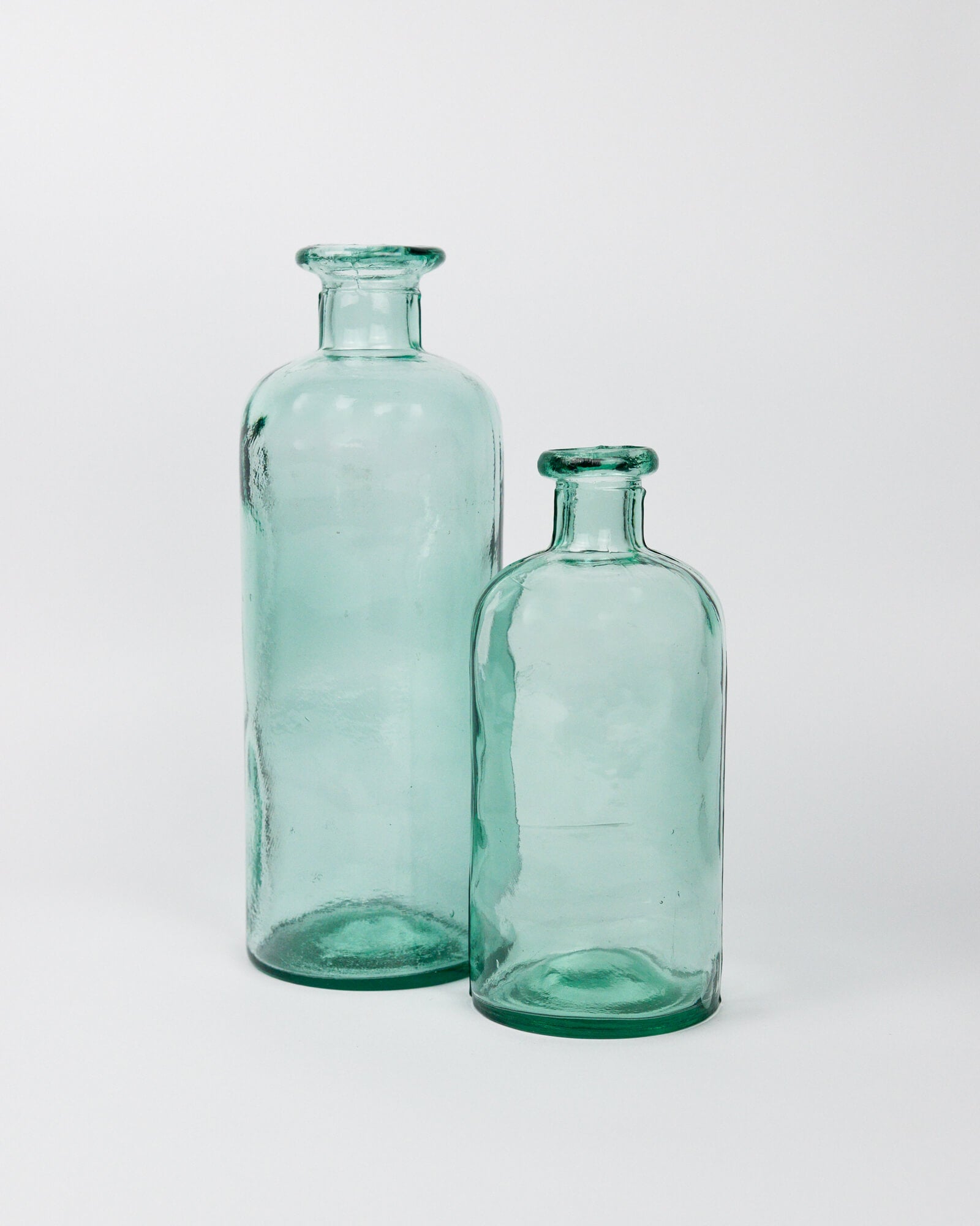 Two green glass bottles on a white background
