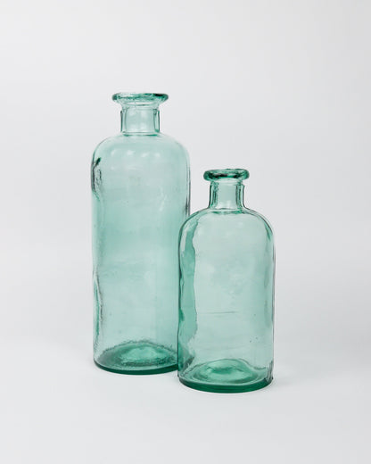 Two green glass bottles on a white background