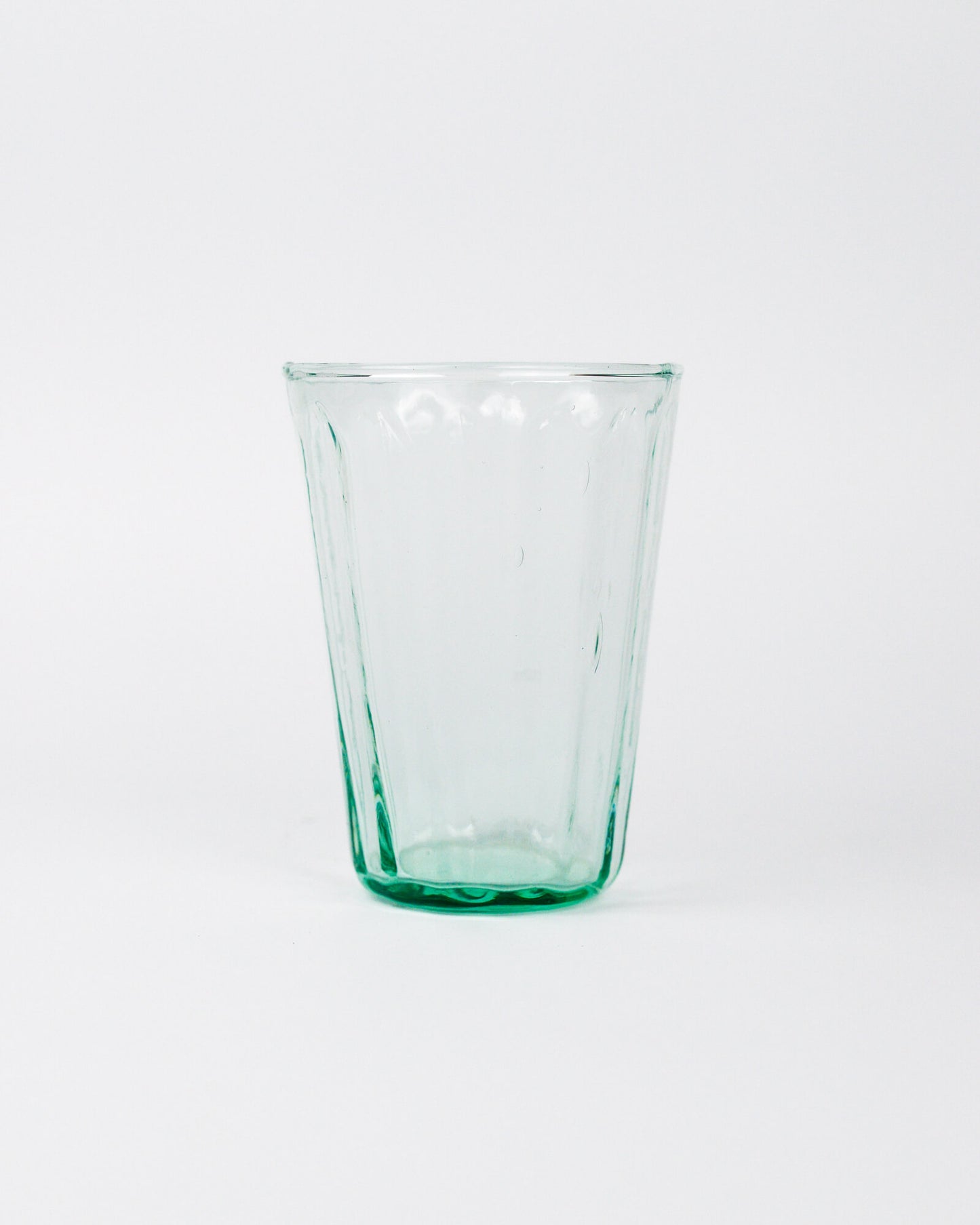 Clear green glass tumbler on a white background
