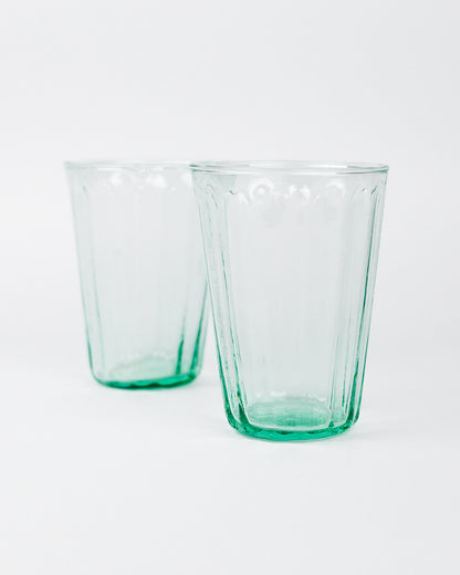 Two green glass tumblers on a white background
