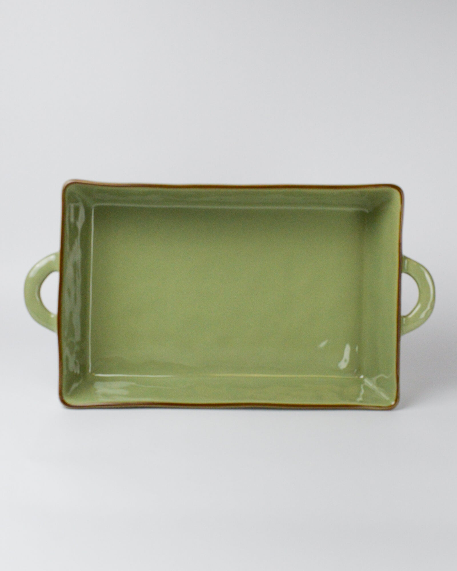 Green rectangular ceramic baking dish with handles on a white background