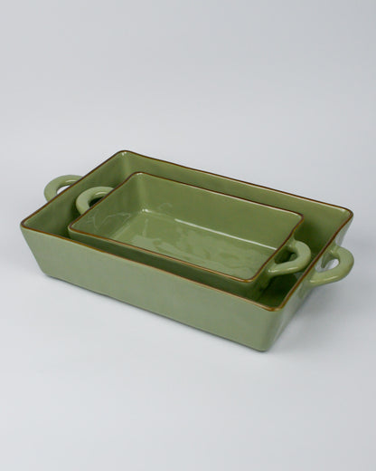 Set of two green ceramic baking dishes with handles on a white background