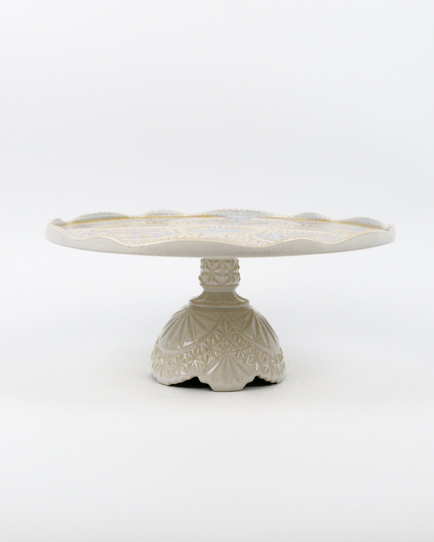 Ceramic cake stand with decorative base on a white background