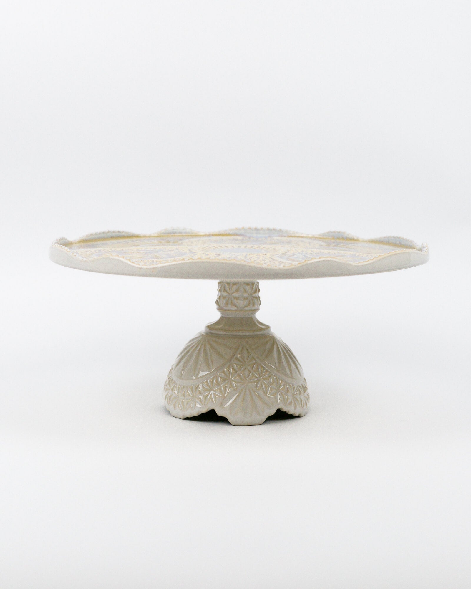 Ceramic cake stand with decorative base on a white background
