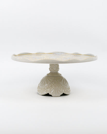 Ceramic cake stand with decorative base on a white background