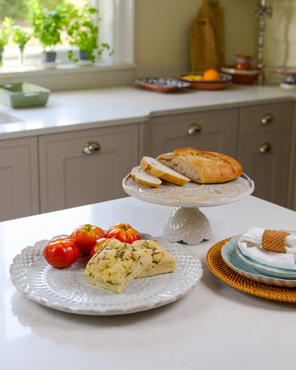 Kitchen counter with bread, tomatoes, and a cake stand.