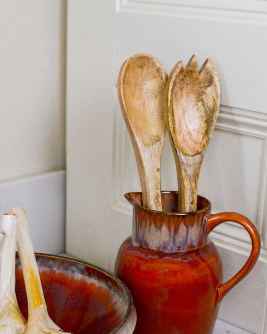 Salad servers on display in a ceramic pitcher 
