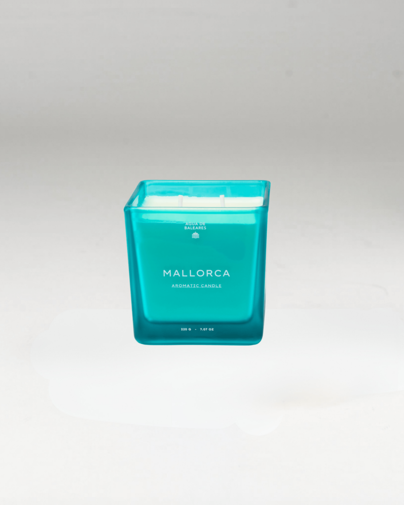 A teal blue square glass jar candle with white wax and white text reading 'MALLORCA' and 'AROMATIC CANDLE' on a white background.