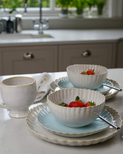 Two cream scalloped edge cereal bowls on a white marble surface 