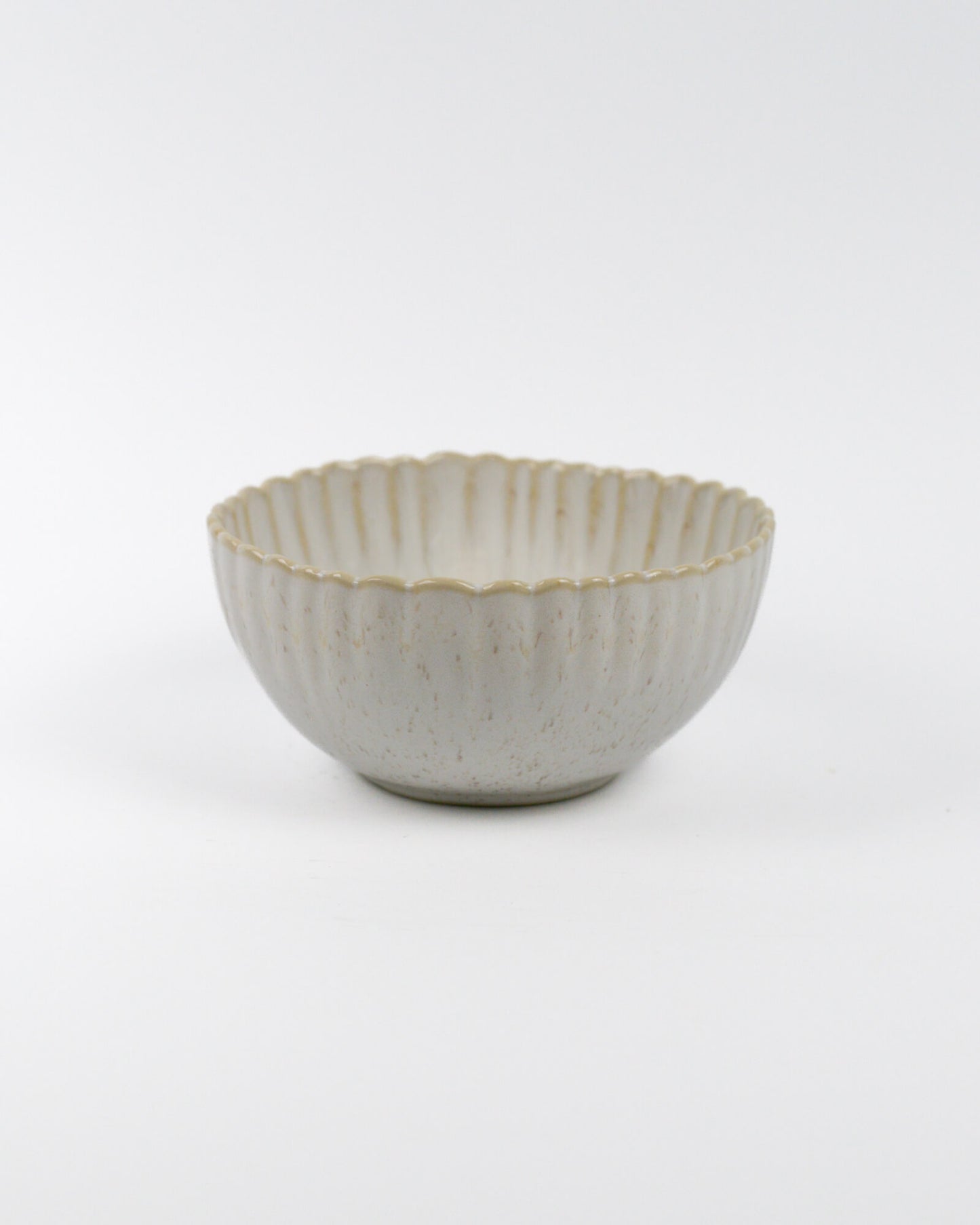 Ceramic cereal bowl with textured surface and scalloped edge on a white background