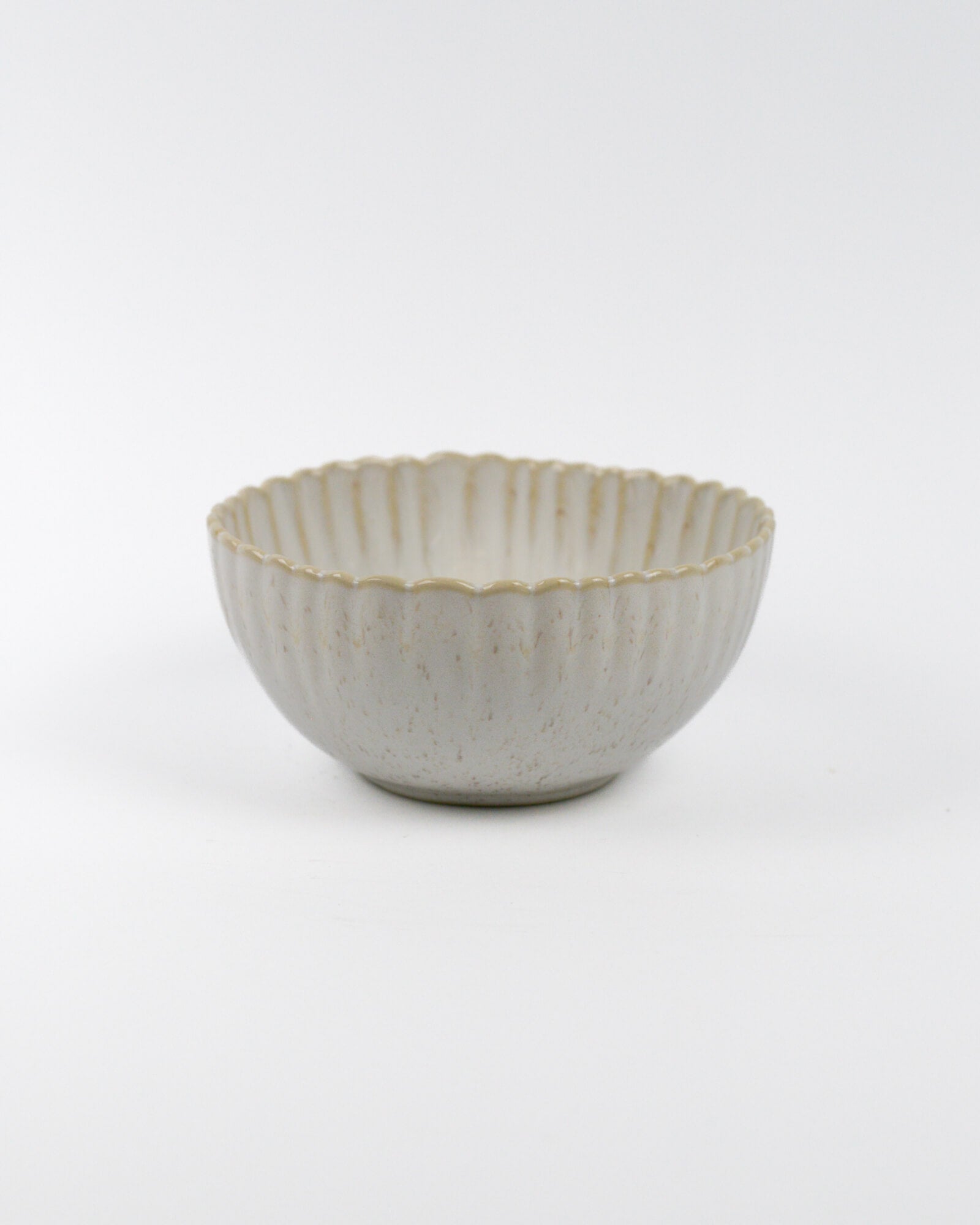 Ceramic cereal bowl with textured surface and scalloped edge on a white background