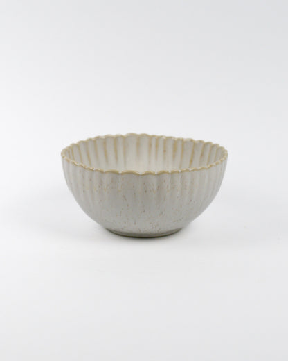 Ceramic cereal bowl with textured surface and scalloped edge on a white background