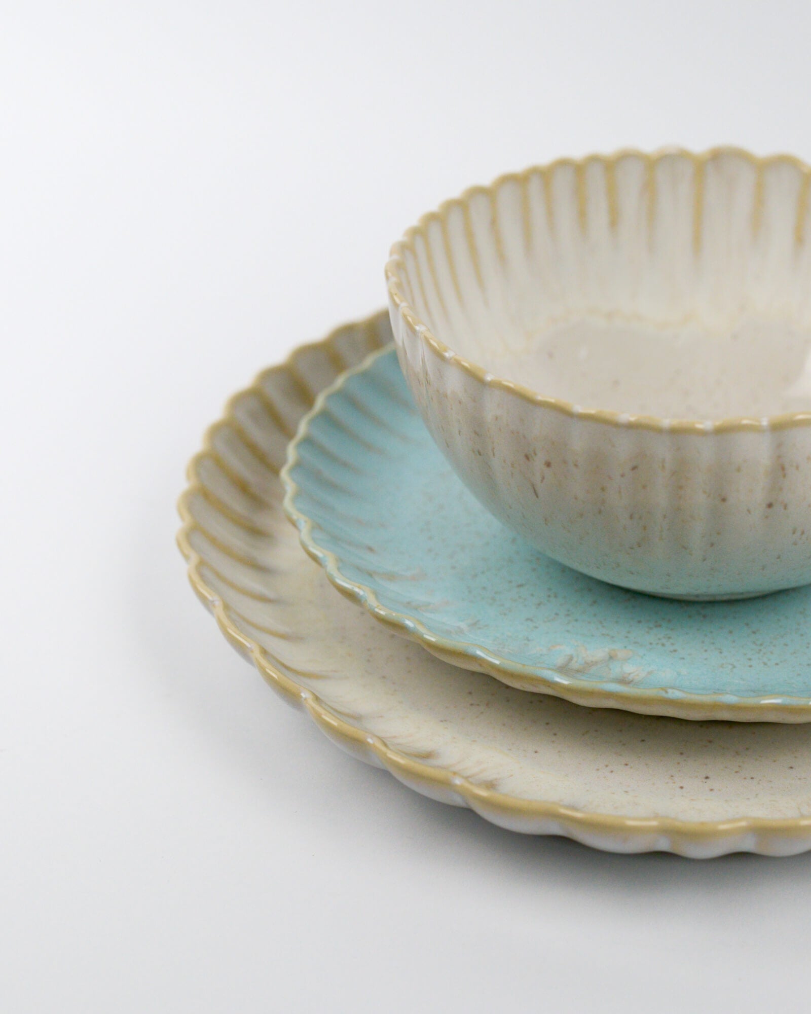 Set of ceramic plates and cereal bowl with scalloped rims on a white background