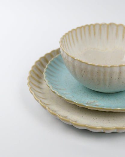 Set of ceramic plates and cereal bowl with scalloped rims on a white background