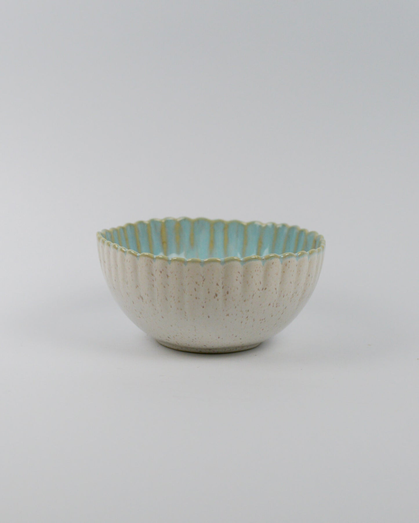 Ceramic bowl with textured surface and scalloped edge on a white background