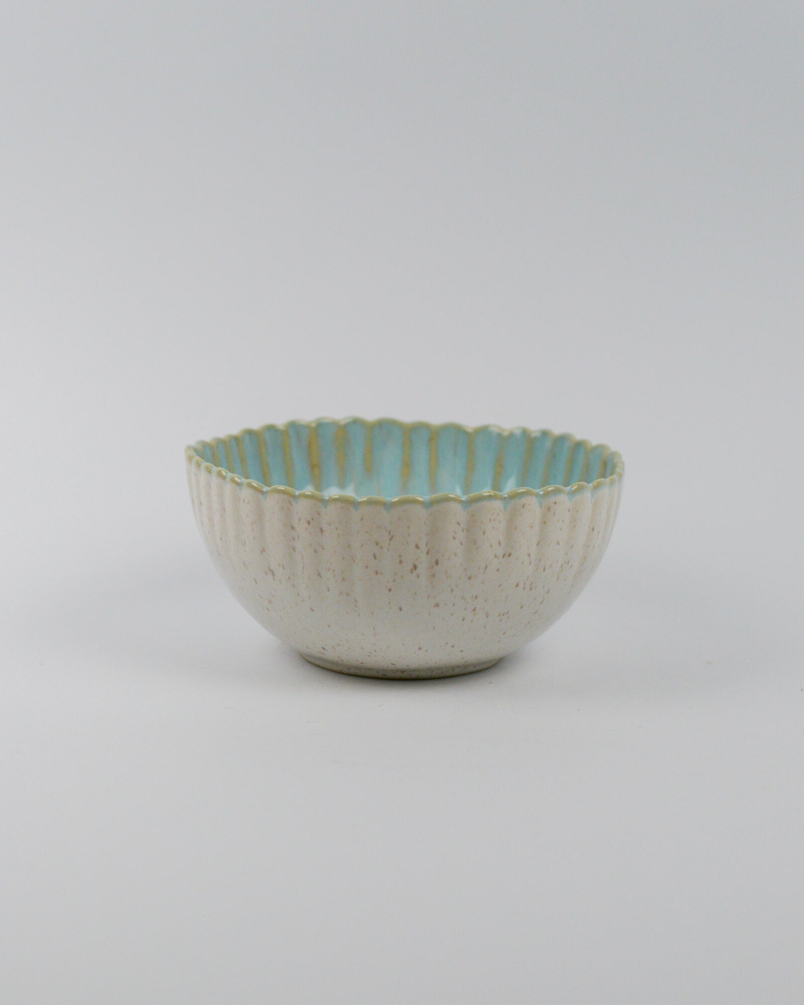 Ceramic bowl with textured surface and scalloped edge on a white background