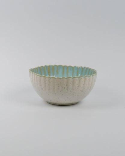 Ceramic bowl with textured surface and scalloped edge on a white background