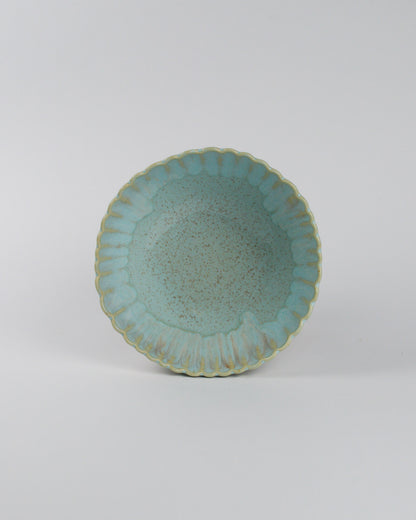 Sky blue ceramic cereal bowl with scalloped edge on a white background