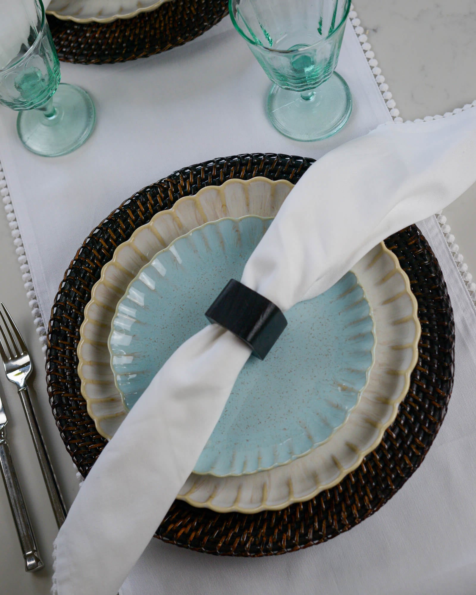White linen coloured scalloped edge dinner plate layered with a light blue scalloped edge salad plate with a linen napkin 