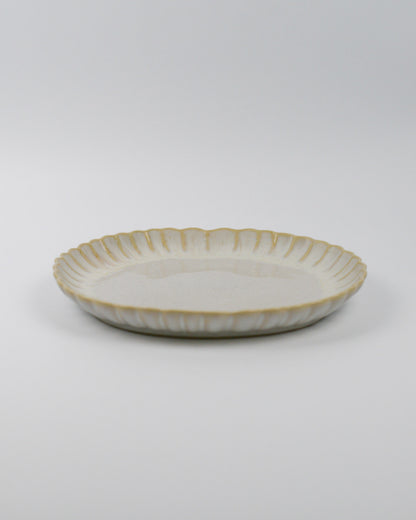 Ceramic stoneware plate with a scalooped edge on a white background