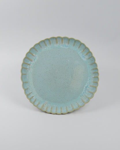 Light blue ceramic stoneware dinner plate with scalloped edge on a white background