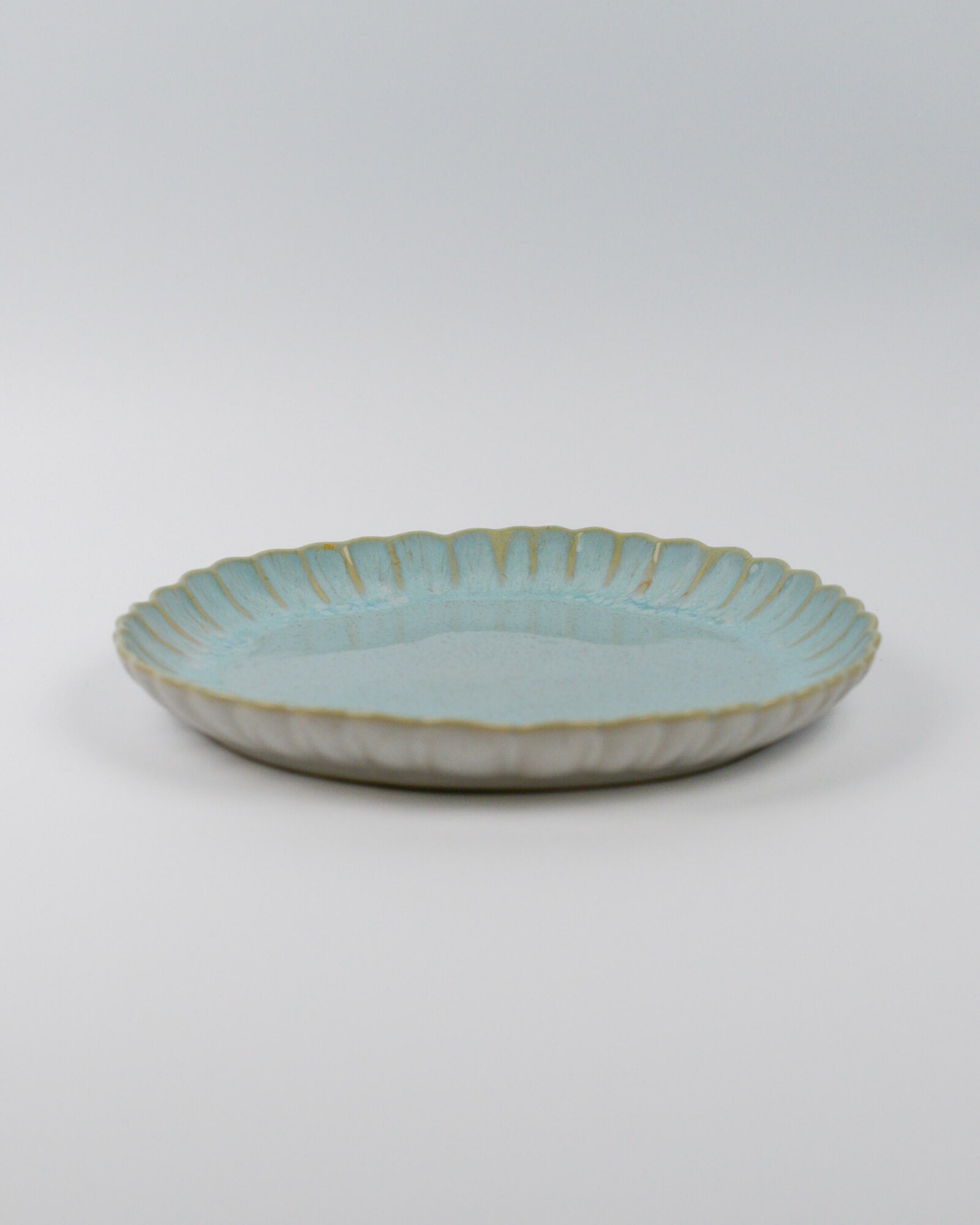 Light blue ceramic dinner plate with a textured edge on a white background