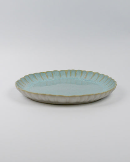 Light blue ceramic dinner plate with a textured edge on a white background