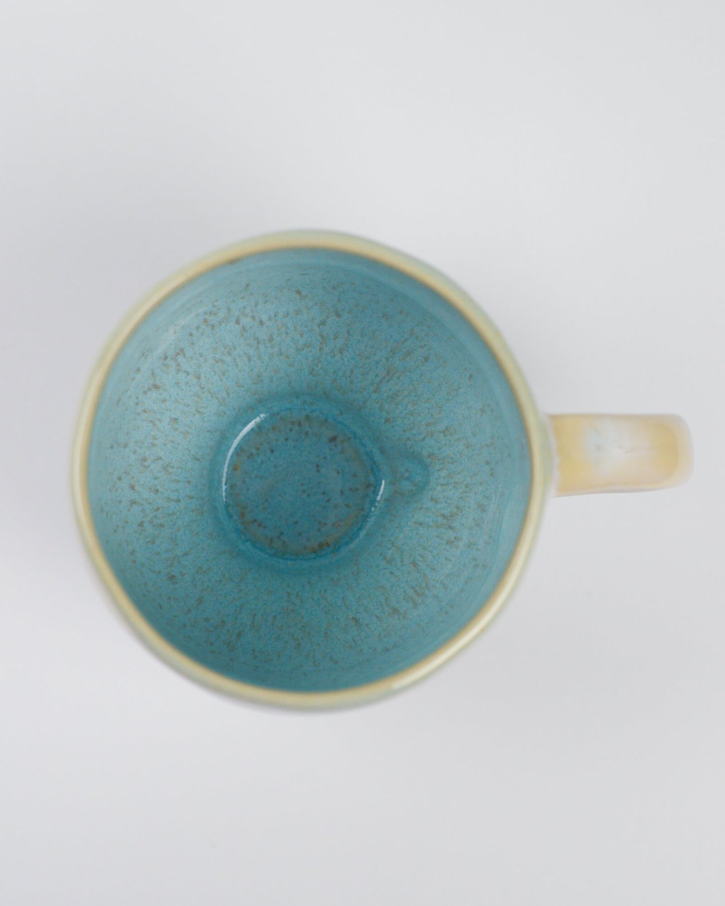 Sky blue ceramic cup with beige handle on a white background