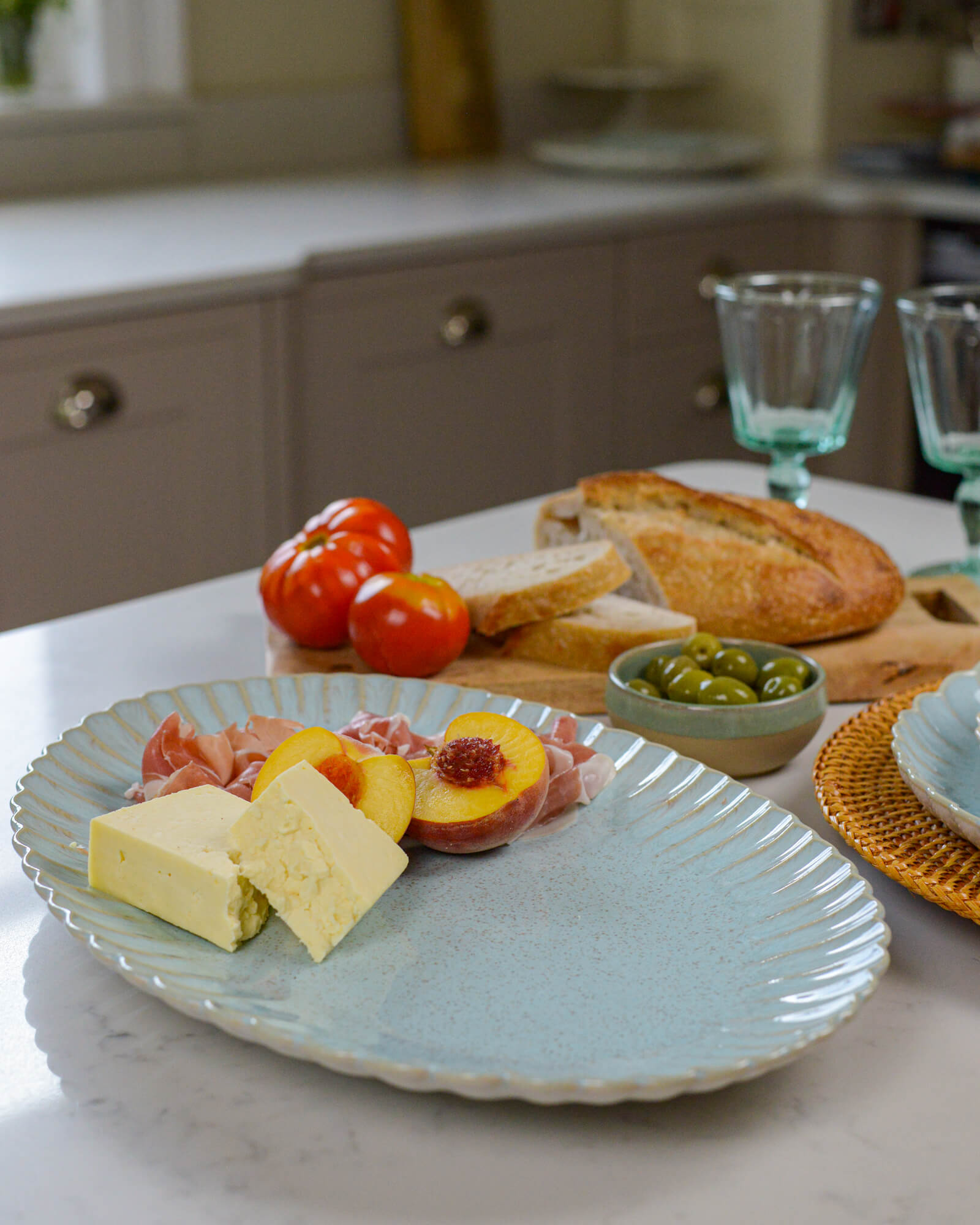 Large oval serving platter with appetizers including cheese, fruit, and cured meats on a marble countertop.