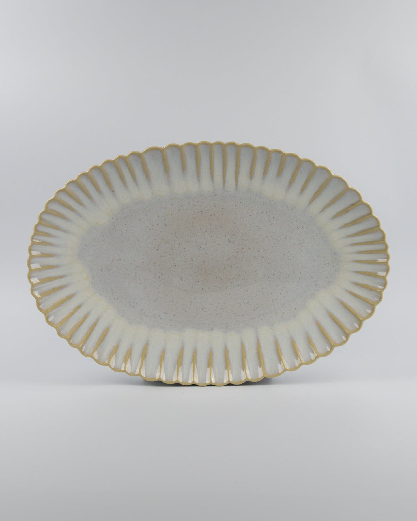 Decorative ceramic oval serving platter with scalloped edge on a white background