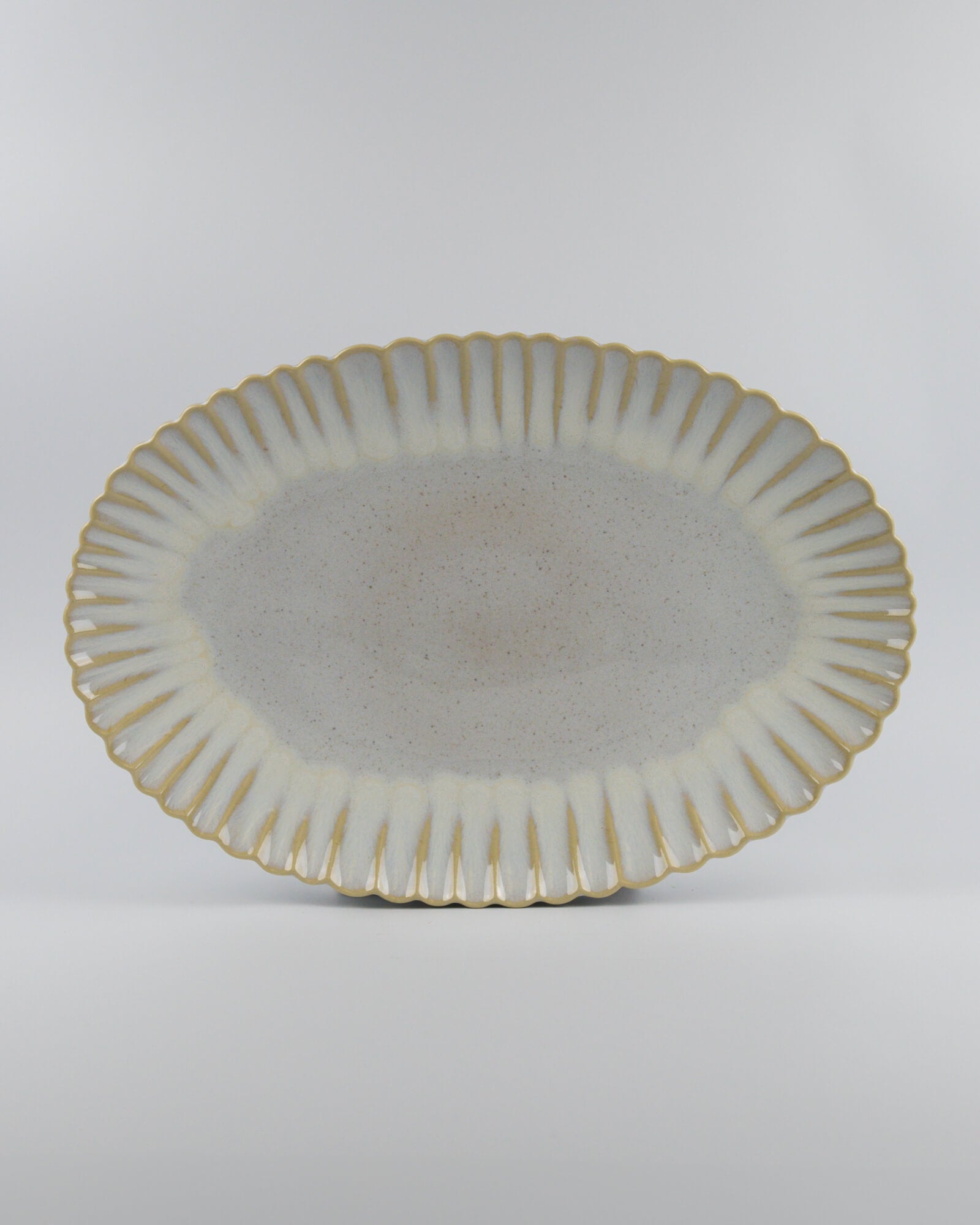Decorative ceramic oval serving platter with scalloped edge on a white background