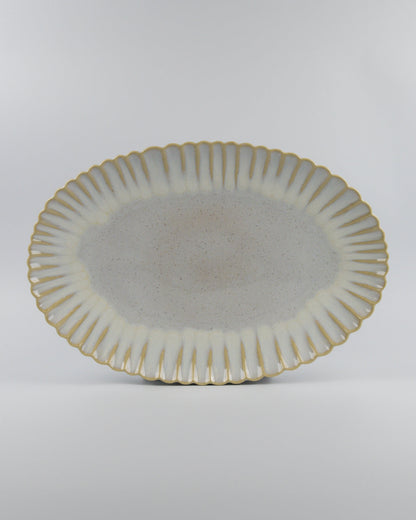 Decorative ceramic oval serving platter with scalloped edge on a white background