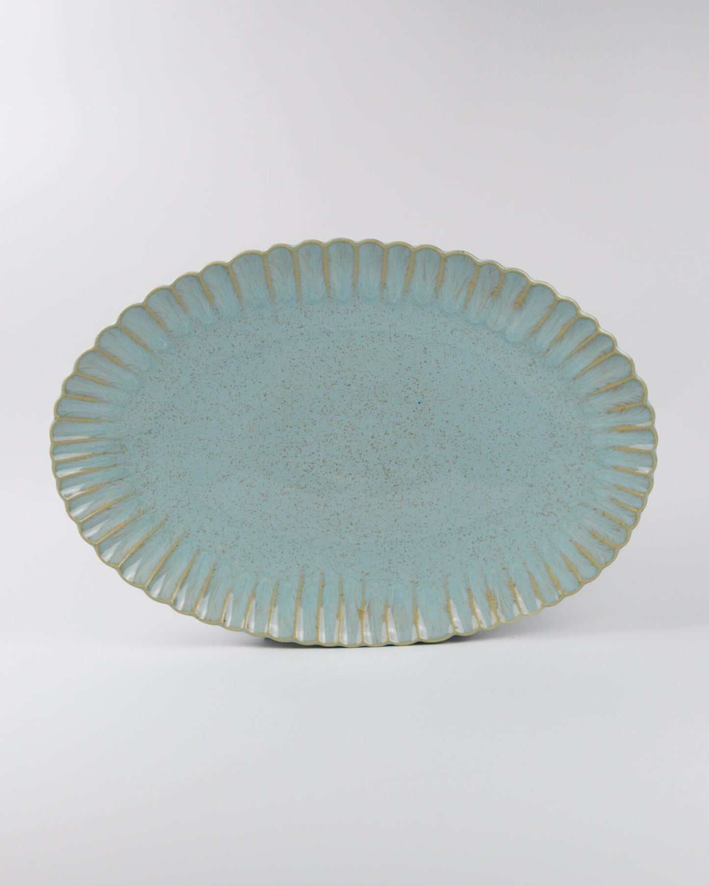 Blue ceramic oval serving platter with textured rim on a white background