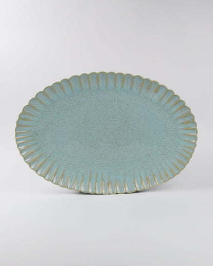 Blue ceramic oval serving platter with textured rim on a white background