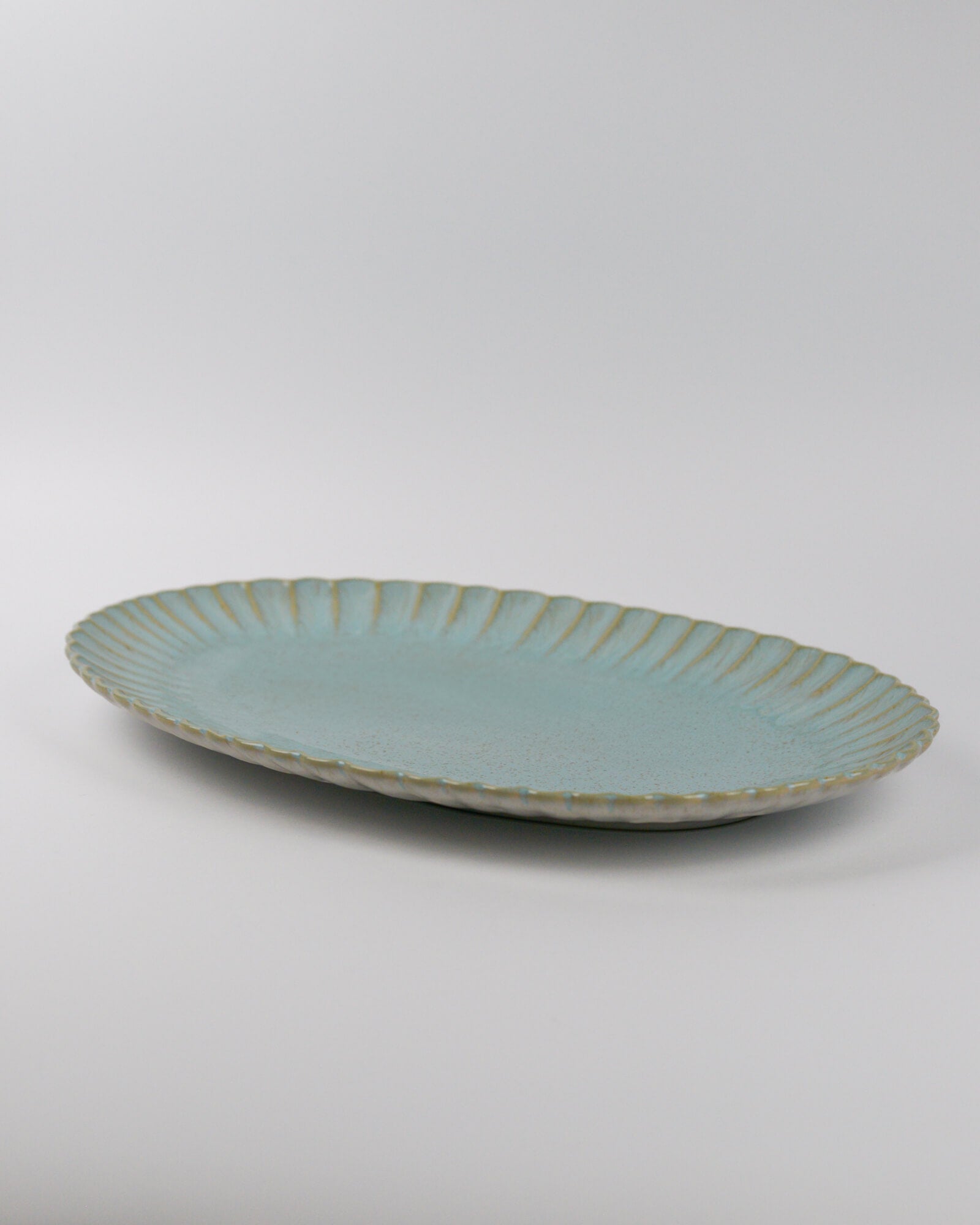 Light blue ceramic platter with textured rim on a white background