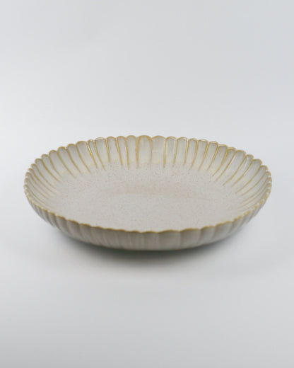 Large ceramic serving dish with decorative edge on a white background