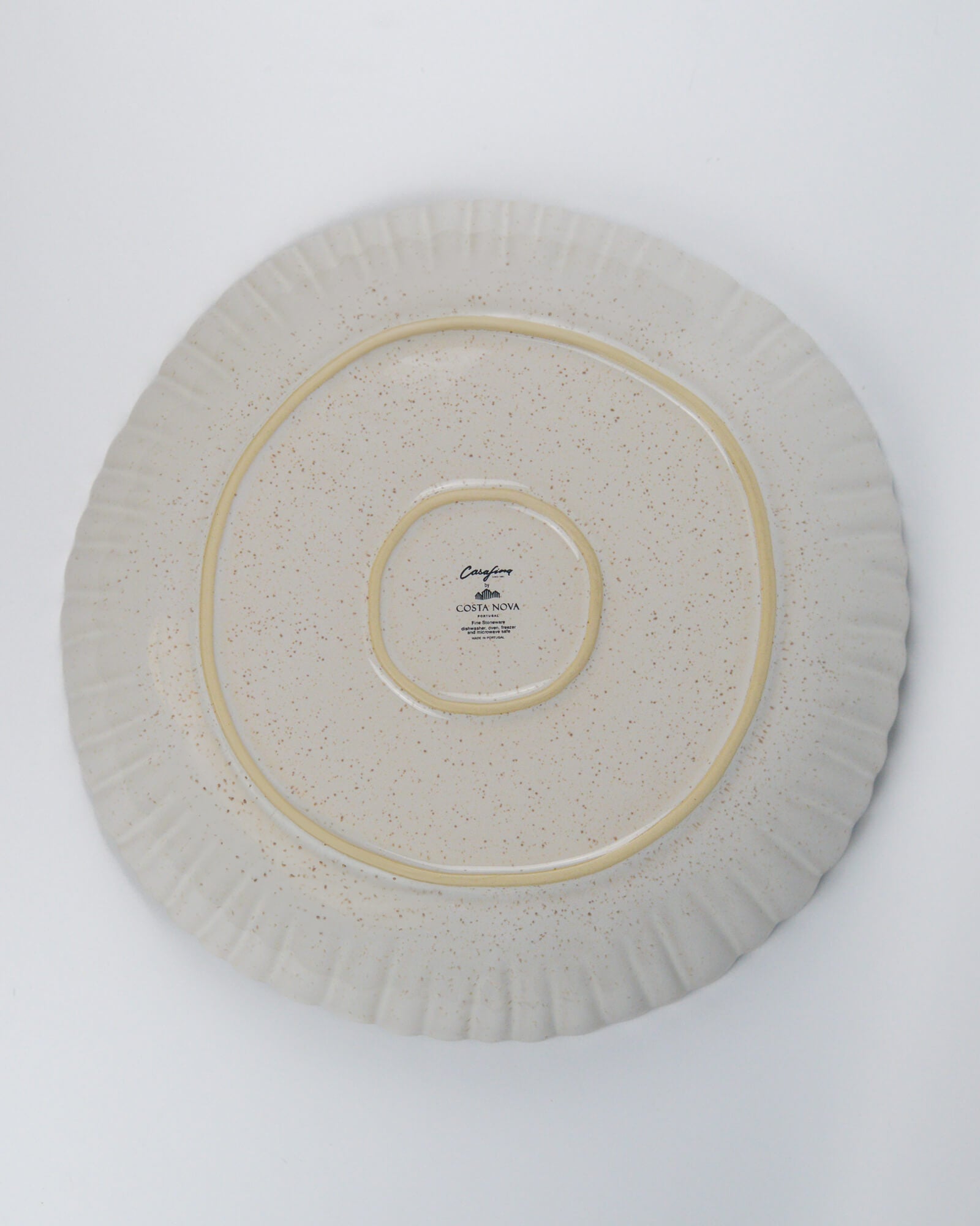 Round ceramic serving dish with a scalloped rim on a white background