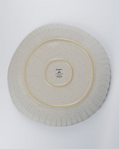 Round ceramic serving dish with a scalloped rim on a white background