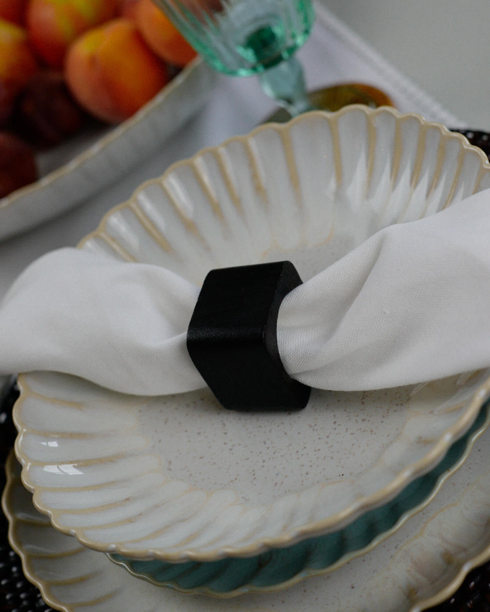 Decorative stoneware pasta bowl with a scalloped edge with a white napkin and dark wooden napkin ring. 