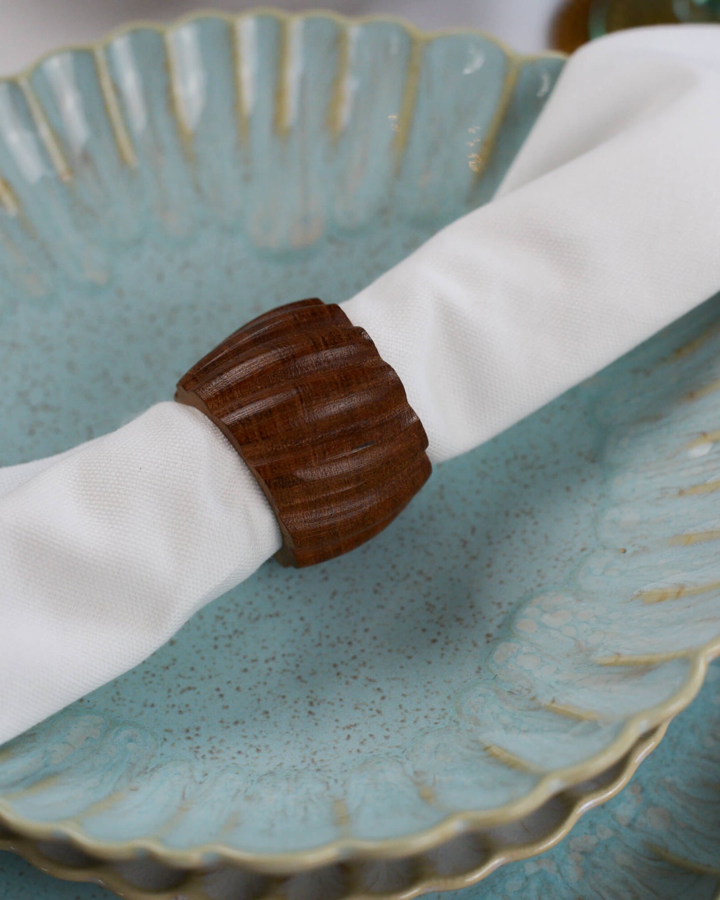 Wooden napkin ring on a white napkin over a textured blue pasta bowl