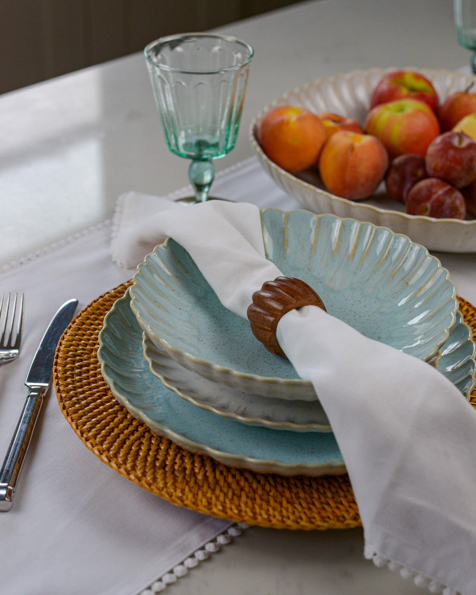 Blue scalloped edge pasta bowl layered on a linen coloured salad plate and sky blue dinner plate on a marble surface