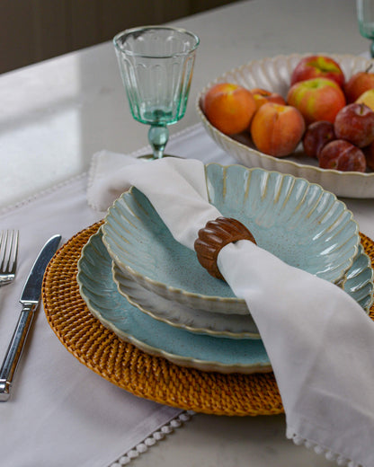 Blue scalloped edge pasta bowl layered on a linen coloured salad plate and sky blue dinner plate on a marble surface