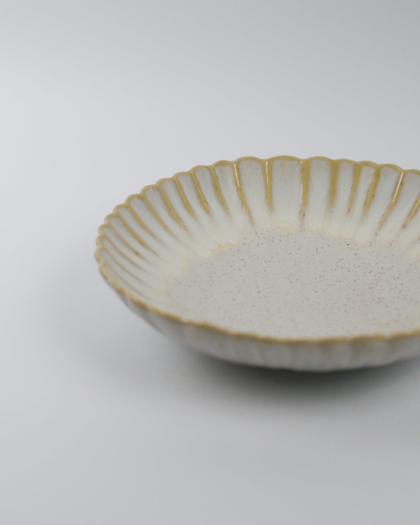 Ceramic pasta dish with scalloped rim on a white background