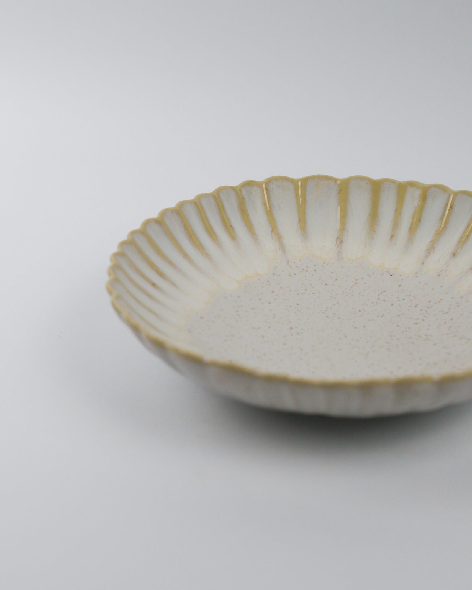 Ceramic pasta dish with scalloped rim on a white background
