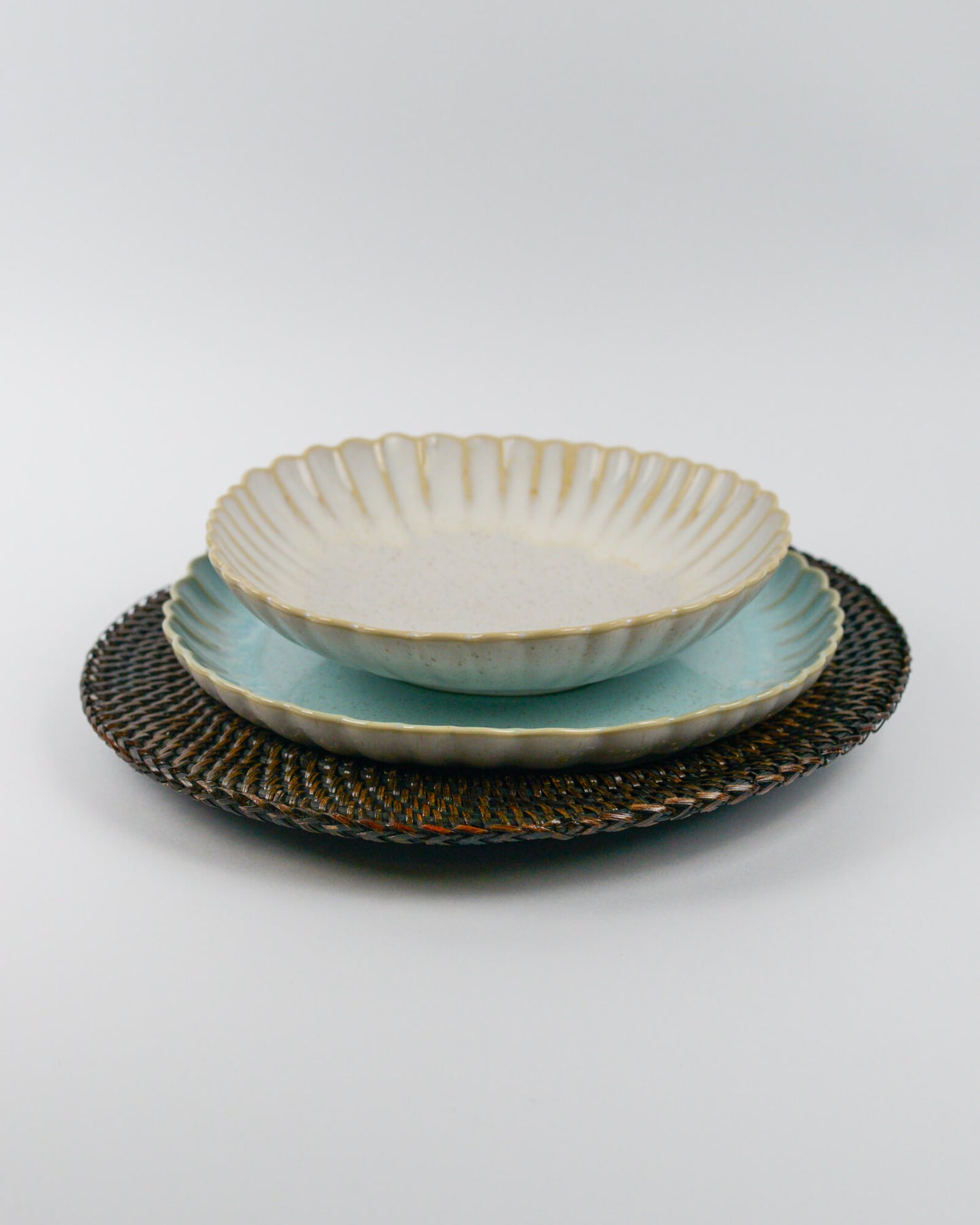 Ceramic pasta bowl with textured glaze on a light blue salad plate on a white background