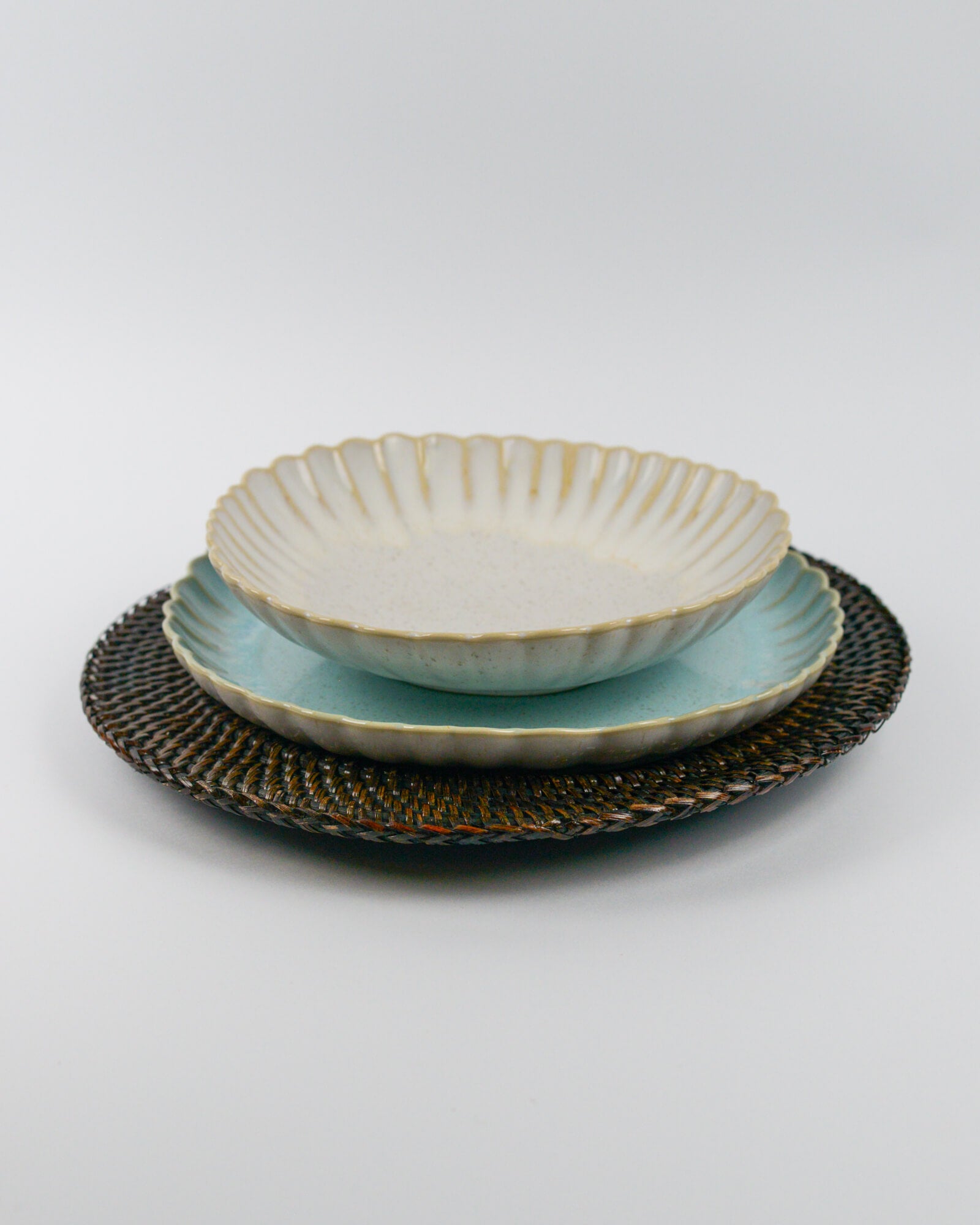 Ceramic pasta bowl with textured glaze on a light blue salad plate on a white background