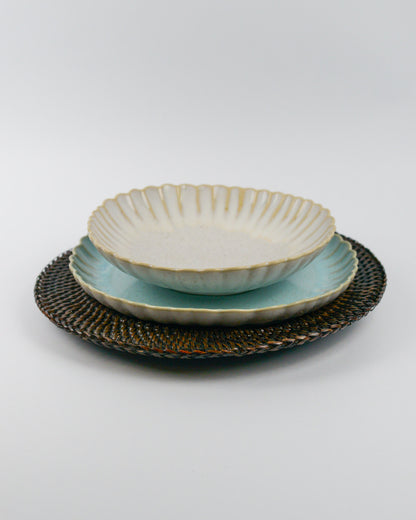Ceramic pasta bowl with textured glaze on a light blue salad plate on a white background