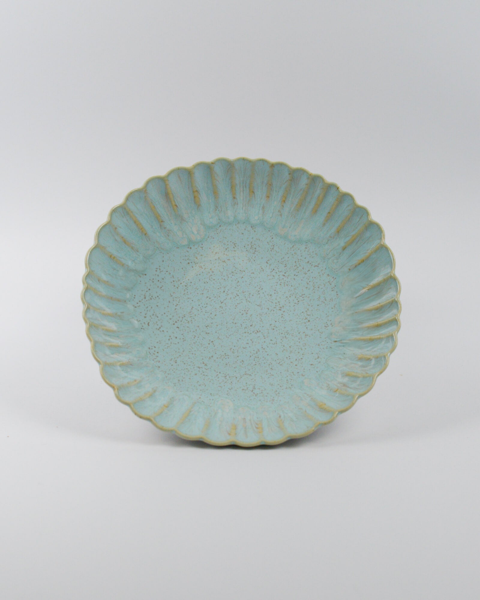 Light blue ceramic pasta bowl with decorative edge on a white background